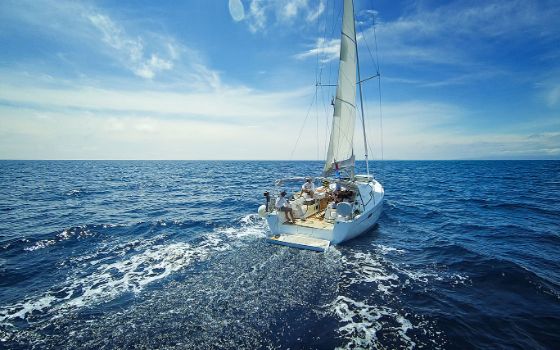 Mehrere Personen sitzen auf einem modernen Segelboot während der Fahrt auf dem Meer.