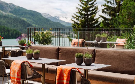 Auf der Terrasse eines Hotels stehen Sofas mit Tischen und Stühlen. 