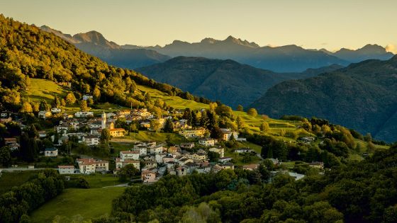 Ein kleines Dorf mit weissen Häusern und einer Kirche liegt in einer Berglandschaft. 