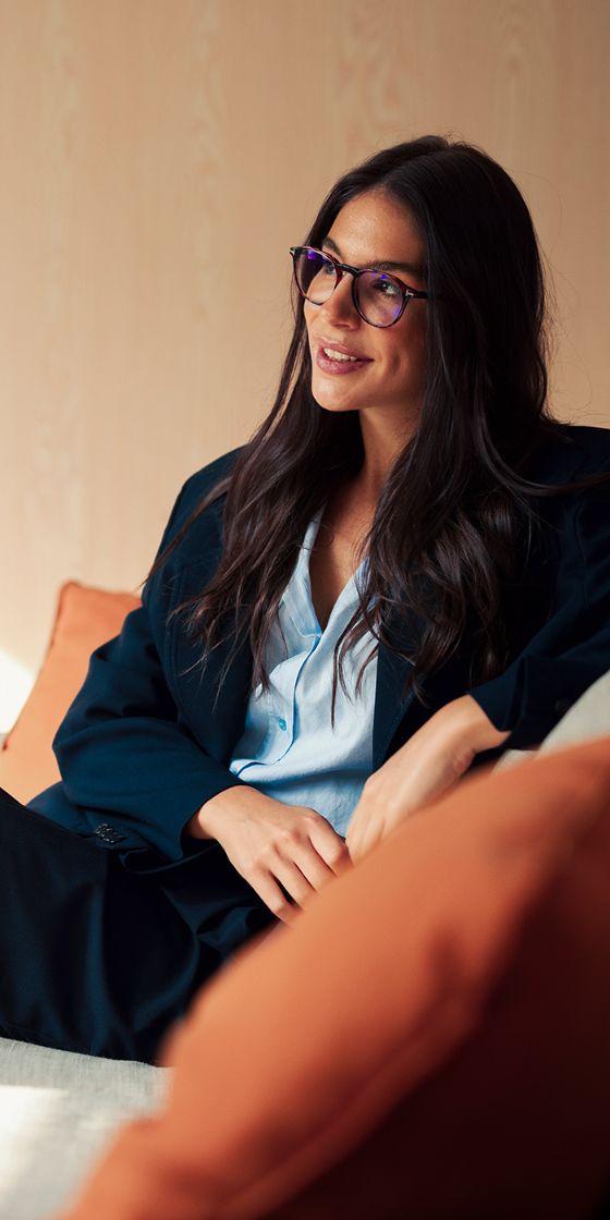 Eine Frau sitzt auf einem Sofa und schaut in die Ferne.