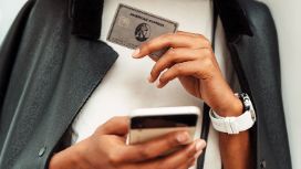 Nahaufnahme einer American Express Platinum Kreditkarte und eines Smartphones in den Händen einer Frau