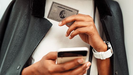 Nahaufnahme einer American Express Platinum Kreditkarte und eines Smartphones in den Händen einer Frau