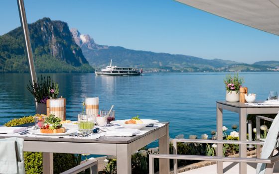Auf einer Terrasse ist ein Tisch für das Frühstück gedeckt und steht direkt am Vierwaldstättersee.