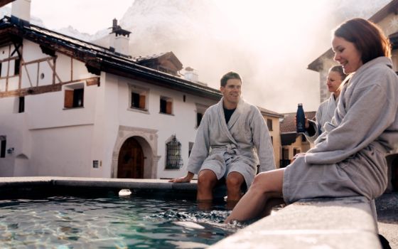 Gäste in Bademänteln entspannen in einem Thermalbad im Engadin