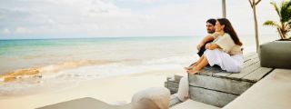 Paar sitzt entspannt auf einer Strandterrasse mit Blick auf das Meer