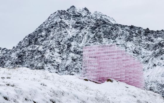 Eine skulpturale Kunstinstallation aus pinkfarbenen Gitterplatten in einer schroffen, schneebedeckten Berglandschaft.