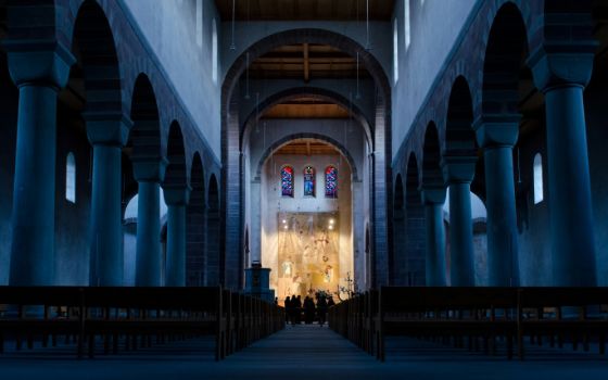 Innenraum des Klosters Allerheiligen in Schaffhausen mit Säulenhalle, Bänken und beleuchtetem Altar.