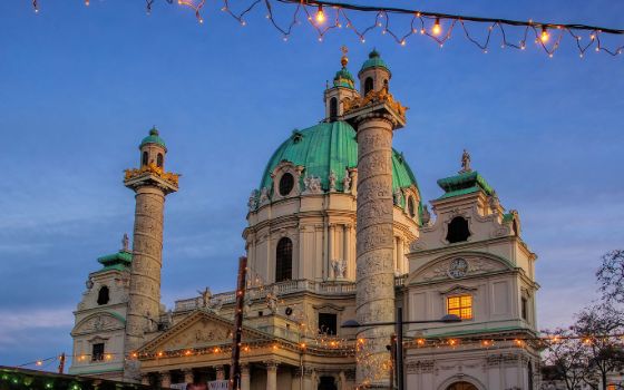 Abendliche Ansicht der Karlskirche in Wien mit Weihnachtsbeleuchtung im Vordergrund.