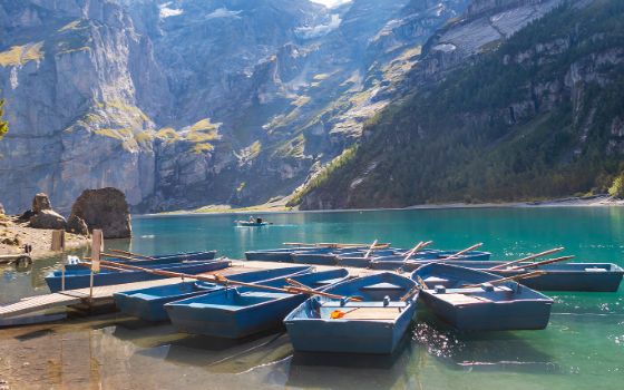 Ruderboote am Ufer des Oeschinensees mit Blick auf türkisfarbenes Wasser und steile Bergwände