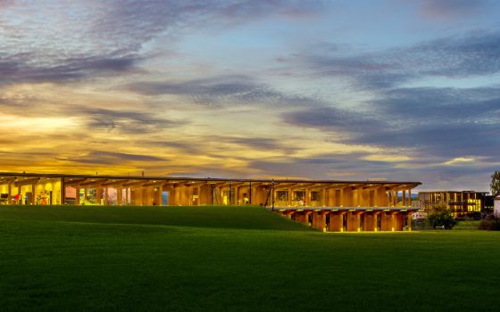 Übungsanlage des Golfparks Holzhäusern mit grüner Wiese im Vordergrund bei Sonnenuntergang.