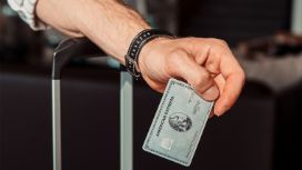 Nahaufnahme eines Unterarms, der sich mit einer Platinum Card in der Hand auf einen Koffergriff stützt