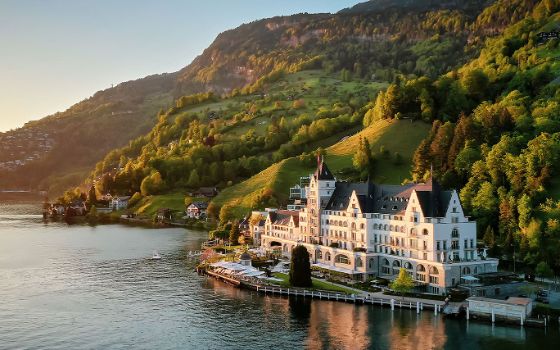 Direkt am Vierwaldstättersee steht ein grosses Hotel an einem Berg.