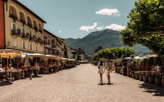 Ein Mann und eine Frau gehen Arm in Arm auf ein idyllisches Landhotel zu.