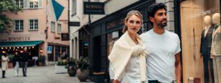 Ein junges Paar spaziert in einer Einkaufsstrasse mit Geschäften.