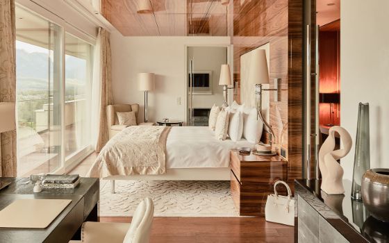 Doppelbett an einem Fenster mit Panoramablick in einem modernen Hotelzimmer mit Designelementen. 