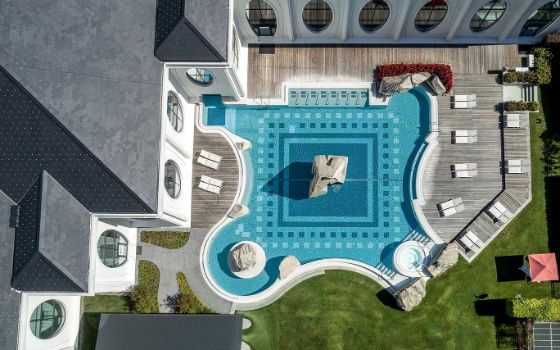 Luftaufnahme eines Hotels mit Blick auf den Aussenpool und Liegen. 