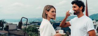 Paar geniesst Kaffee auf Dachterrasse mit Blick auf Zürich und die Alpen