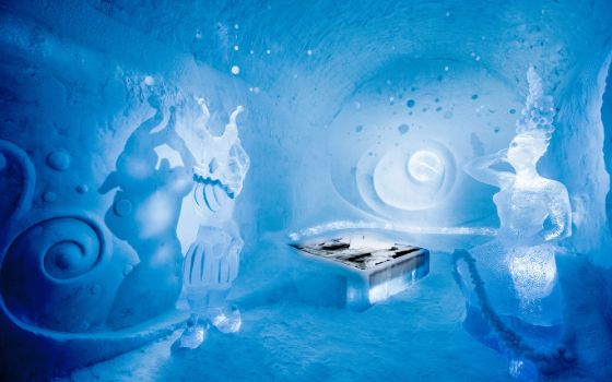 In einem Raum aus Eis stehen Eisskulpturen um ein Bett, auf dem Felle liegen.