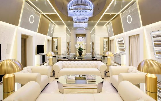 Luxuriöse, futuristisch wirkende Hotelsuite mit weissem Mobiliar und goldenen Dekorationselementen. 