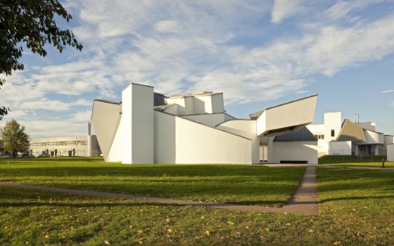 Ein markantes weisses Museumsgebäude, das von Architekt Frank Gehry desgined wurde, umgeben von grüner Wiese an einem sonnigen Tag. 