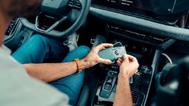 Ein Mann sitzt im Auto und zieht eine Kreditkarte aus einem Portemonnaie.