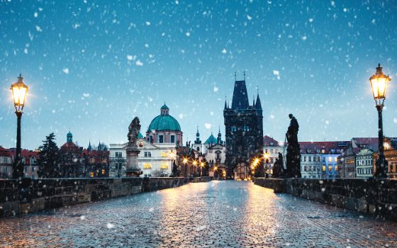 Winterliche Karlsbrücke in Prag mit Schneefall und Blick auf den Altstädter Brückenturm.