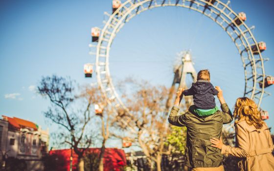 Familie vor dem Riesenrad im Wiener Prater bei blauem Himmel und Herbstlicht