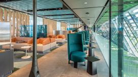Helle Flughafenlounge mit modernen Polstermöbeln in unterschiedlichen Farben und Glasfassade.