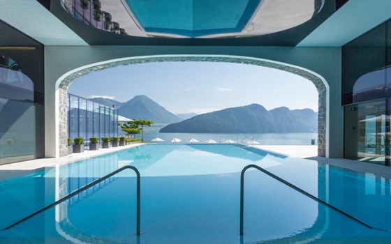 Ein großer Swimmingpool bietet durch eine Öffnung Blick auf eine Berglandschaft. 