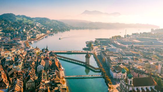 Luftaufnahme von Luzern mit Kapellbrücke, Wasserturm, Vierwaldstättersee und Pilatus im Hintergrund, exklusives Reiseziel mit American Express Vorteilen.
