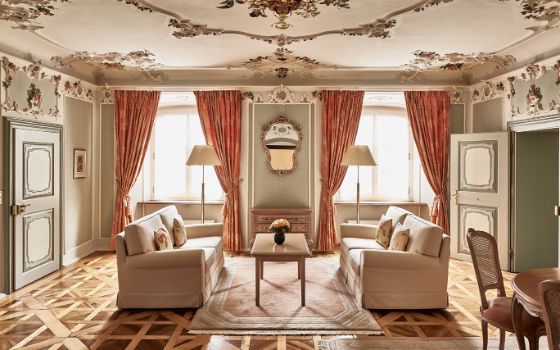 Opulentes Wohnzimmer in Pastelltönen mit Stuckdecke und Parkettboden. 