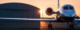 Ein Flugzeug steht im Sonnenuntergang auf einer Landebahn.