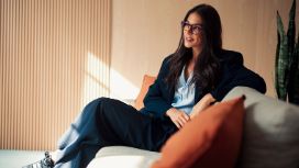 Eine Frau sitzt auf einem Sofa und schaut in die Ferne.