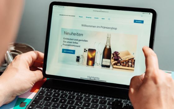 Nahaufnahme von zwei Händen an einem Notebook, auf dem Screen die «Membership Rewards»-Seite von American Express mit Bildern verschiedener Prämien.