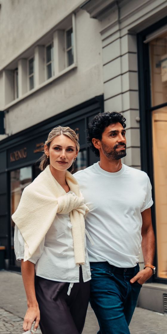 Ein junges Paar spaziert in einer Einkaufsstrasse mit Geschäften.