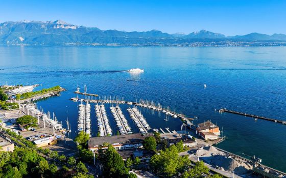 Yachthafen von Ouchy in Lausanne am Genfersee mit Blick auf die Alpen bei strahlend blauem Himmel.