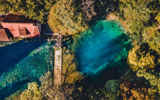 Türkisfarbenes Wasserloch in einem Waldgebiet aus der Vogelperspektive. 