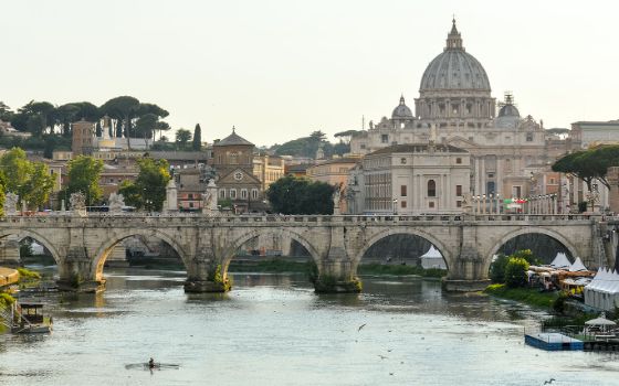 Blick auf den Petersdom in Rom mit der Engelsbrücke über den Tiber im Vordergrund.