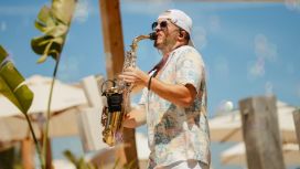 Ein Mann mit kurzem Hemd und Sonnenbrille spielt Saxophon