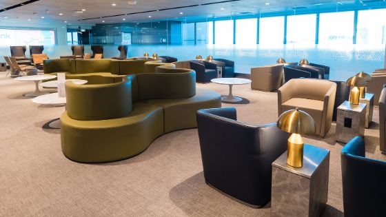 In der The Centurion Lounge am Flughafen in Sydney stehen gemütliche grüne Loungemöbel neben cremefarbenen und anthrazitfarbenen Sesseln. 