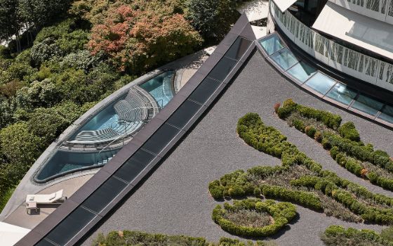 Aufsicht einer begrünten Dachterrasse eines modernen Hotelkomplexes mit Aussenpool.