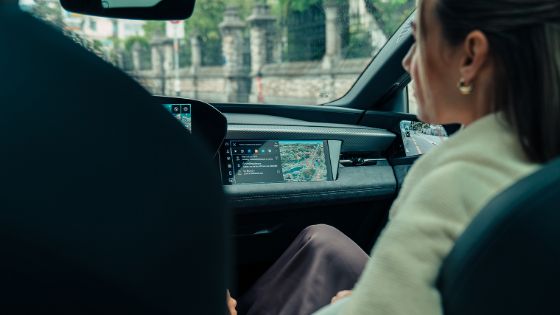 Blick über die Schulter einer Frau auf das Navigationsgerät in der Mittelkonsole eines schicken Autos