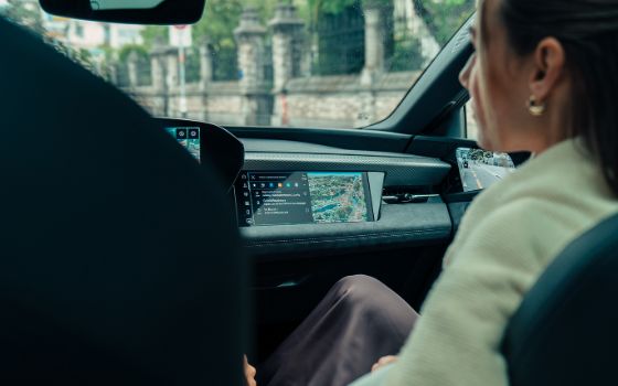 Blick über die Schulter einer Frau auf das Navigationsgerät in der Mittelkonsole eines schicken Autos