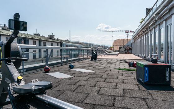 Dachterrasse mit Fitnessgeräten und Sonnenliegen in Innenstadtlage. 