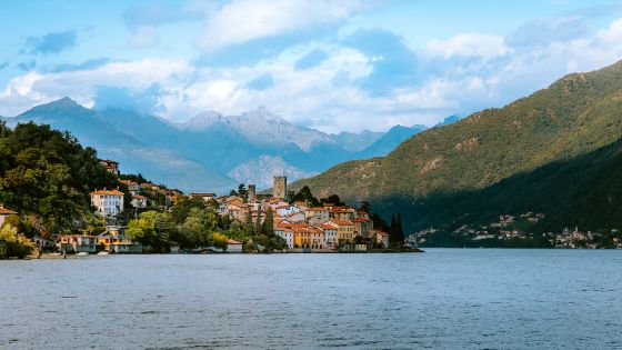 Mediterrane Ortschaft am Ufer eines Sees vor Bergpanorama.