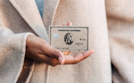 Nahaufnahme einer weiblichen Hand, die eine American Express Gold Card hält.