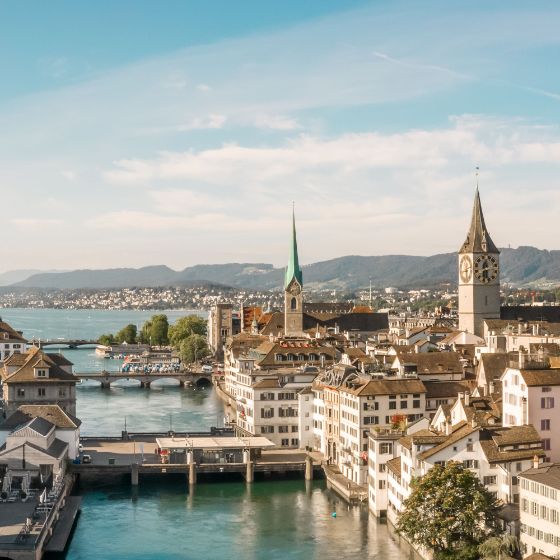 Panoramablick auf Zürich mit der Limmat, historischen Gebäuden und markanten Kirchtürmen bei Tageslicht.