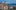 Blick auf die Kathedrale von Lausanne mit ihrem markanten Turm, dahinter die Stadt und der Genfersee mit Alpenpanorama.