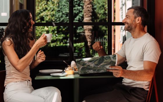Eine Frau und ein Mann sitzen in einem romantischen Hotel an einem Tisch und geniessen ein spätes Frühstück.