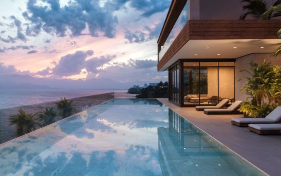 Haus mit Pool und mehreren Liegen, im Hintergrund Meer